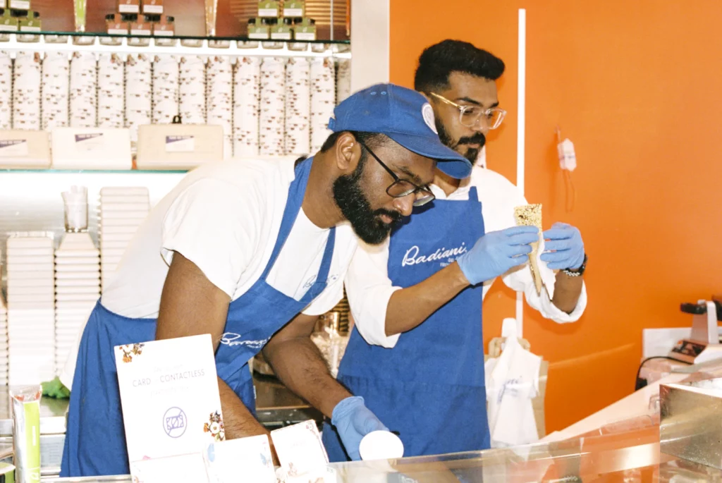 Two people wearing aprons in an ice cream shop