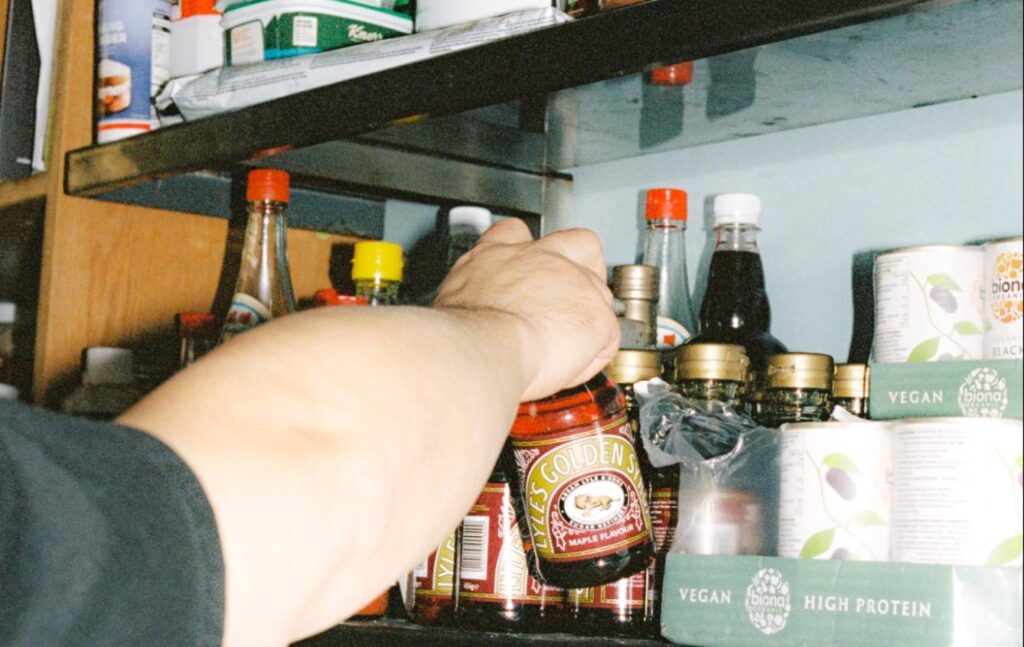 Chef grabbing maple syrup from a shelf of ingredients