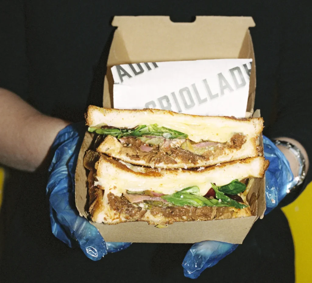 Employee holding a freshly toasted sandwich from Griolladh