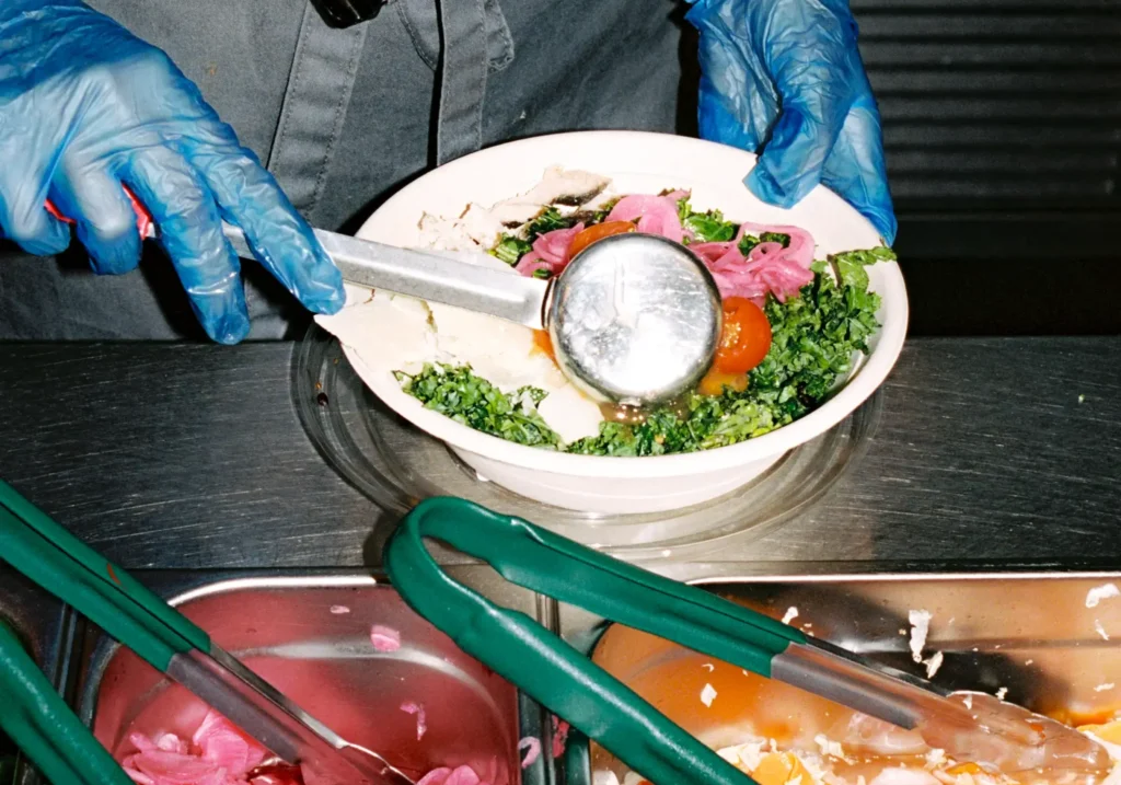 Chef serving fresh vegetables into a bowl from Urban Greens
