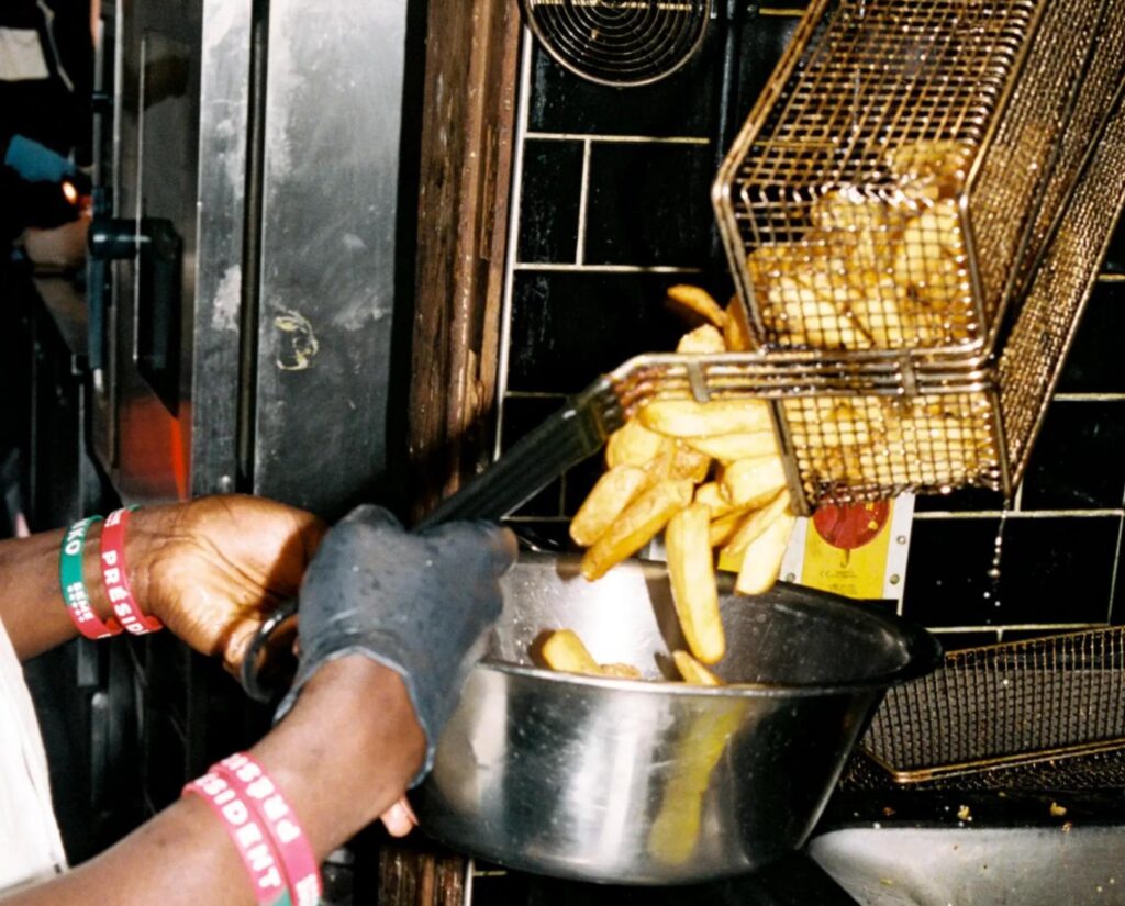 A chef pouring friend chips into a silver bowl