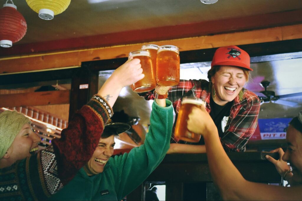 A group of people cheering and holding beers in the air