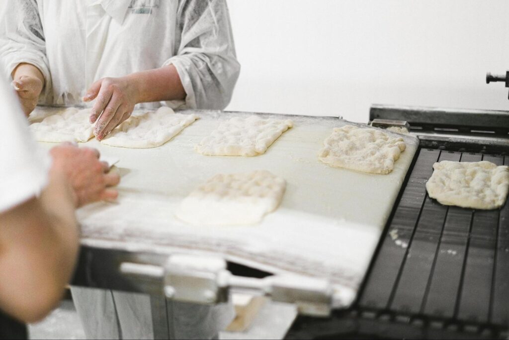 Bakery profit margins: Two bakers preparing foccaccia dough