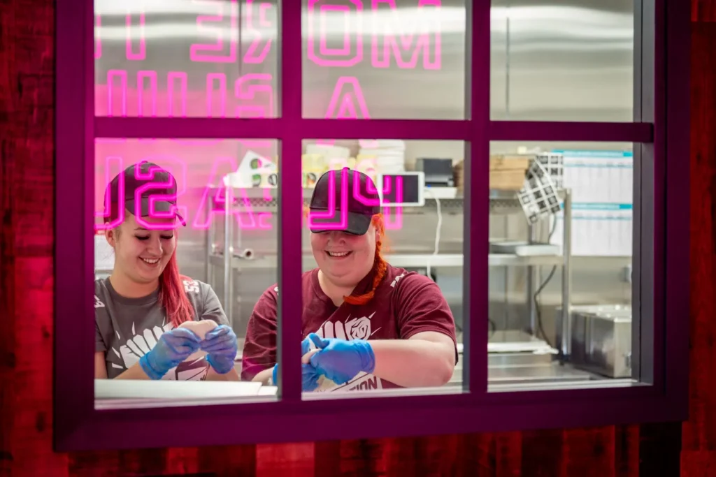 Two restaurant workers smiling and making bread