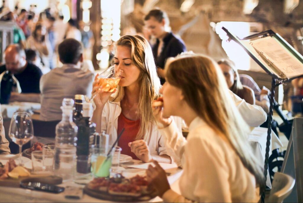 Two friends enjoying food and drink in a restaurant