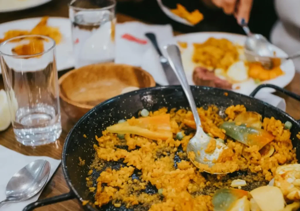 A paella dish at a table with people eating