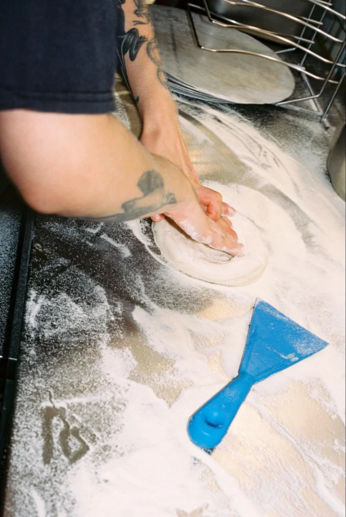 Chef rolling pizza dough on a counter