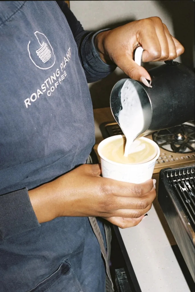 Barista pouring milk into coffee