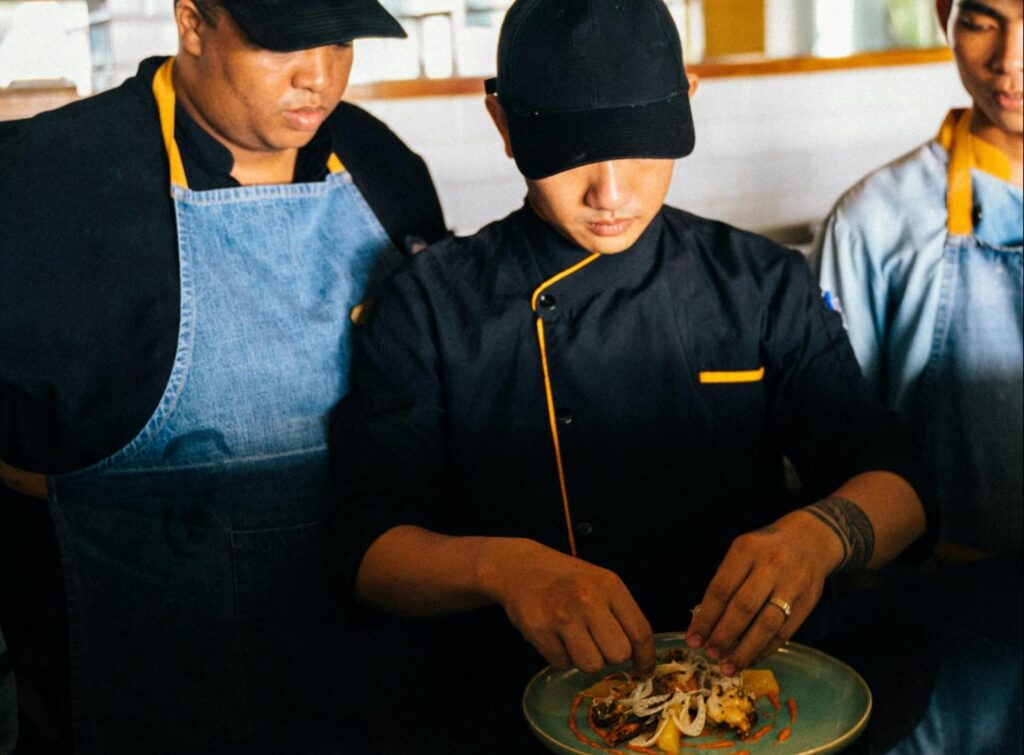 Head chef showing other chefs how to plate a new dish